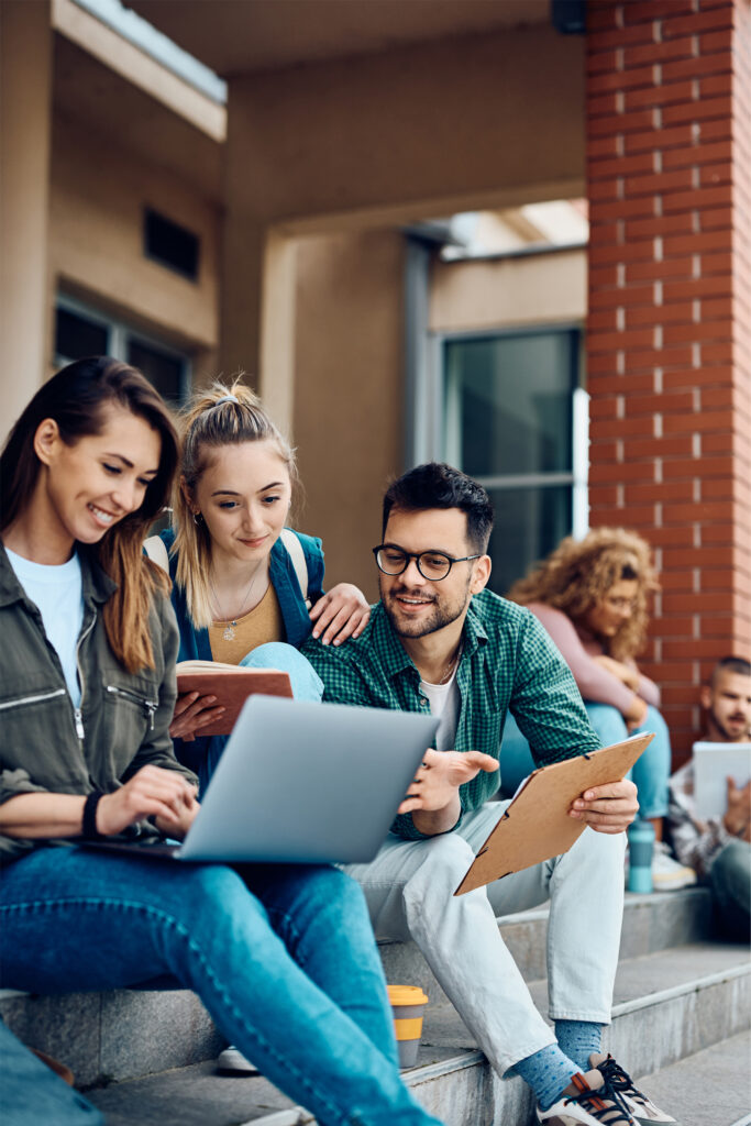 A group of three young adults, who use Bright Future Branding, collaborating on a laptop while sitting on outdoor steps, symbolizing teamwork and shared learning.