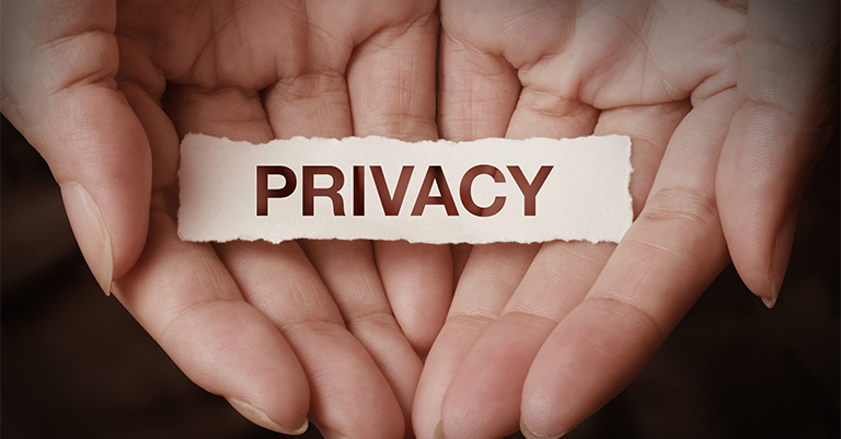 Cupped hands holding a torn paper strip with the word "PRIVACY," symbolizing security, protection, and data privacy awareness.