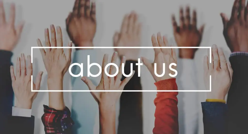 Image of diverse hands raised against a light background, with the words “about us” in bold white font overlaid inside a rectangular frame. The visual emphasizes community, inclusion, and openness, often used to introduce a team or organization.