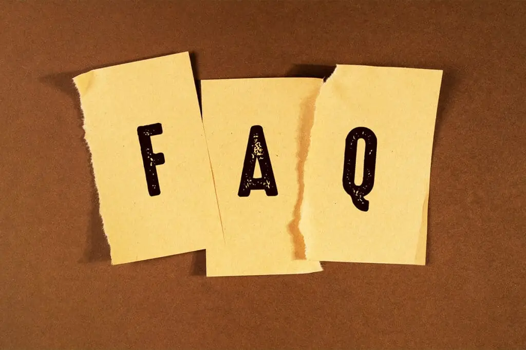 Three torn pieces of paper on a brown background spell out FAQ in bold black letters. The image introduces a frequently asked questions section for anyone looking to Build a Personal Brand.