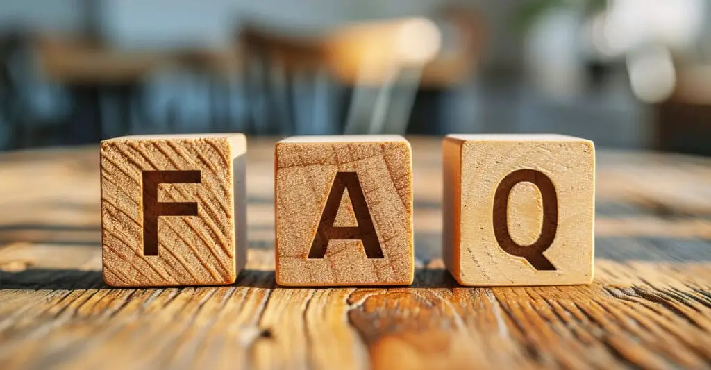 Three wooden letter blocks on a rustic table spell FAQ, with a softly blurred background. Concept image for develop your personal brand by answering common questions and building trust through clear information.