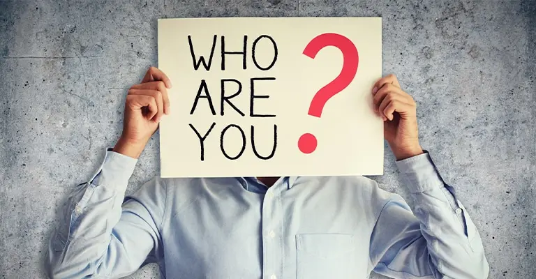 Person in a light blue shirt holds a sign over their face with the text “WHO ARE YOU.” A large red question mark emphasizes identity and self discovery in the context of personal branding.